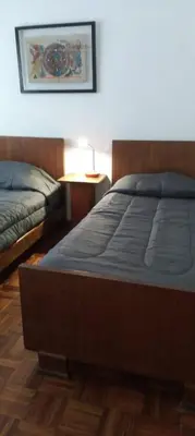 a bedroom with two beds and a table with a lamp at Casa/ Villa General Belgrano in Villa General Belgrano