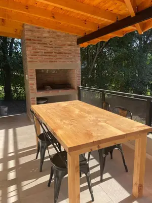 a wooden table and chairs on a patio at La Franca Aparts in Villa General Belgrano