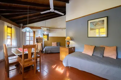 a bedroom with two beds and a table and a desk at POSADA NEHUEN in Villa General Belgrano