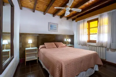 a bedroom with a bed and two tables and a window at POSADA NEHUEN in Villa General Belgrano