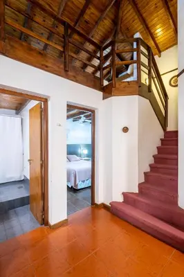 a room with a staircase and a bedroom with a bed at POSADA NEHUEN in Villa General Belgrano