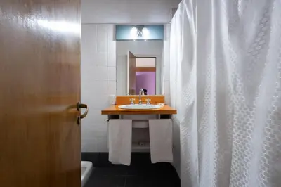 a bathroom with a sink and a shower curtain at POSADA NEHUEN in Villa General Belgrano
