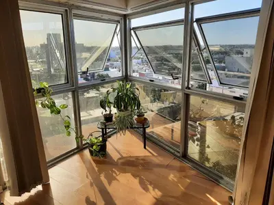 an empty room with a bunch of windows and plants at Departamento MeR in Río Cuarto