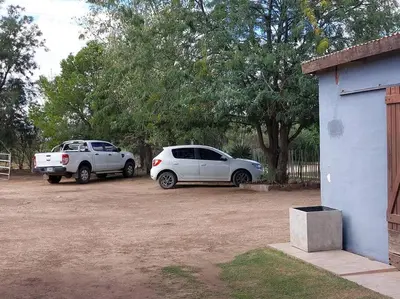 two cars parked in a parking lot next to a building at Cardozo House Monoambiente acogedor y familiar in Villa Dolores