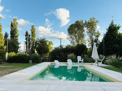 a swimming pool with two chairs and an umbrella at Cardozo House Monoambiente acogedor y familiar in Villa Dolores