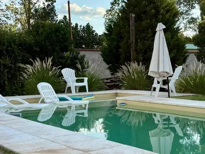 two chairs and an umbrella next to a swimming pool at Cardozo House Monoambiente acogedor y familiar in Villa Dolores