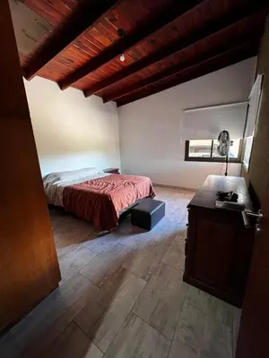 a bedroom with a bed and a table in a room at Casa en Santa Rosa de Calamuchita in Santa Rosa de Calamuchita