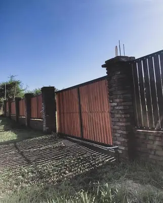 a fence with a red gate and a brick wall at Casa en Santa Rosa de Calamuchita in Santa Rosa de Calamuchita