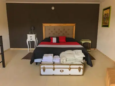 a bedroom with a bed with a suitcase on the floor at Departamentos El Milagro in Tanti