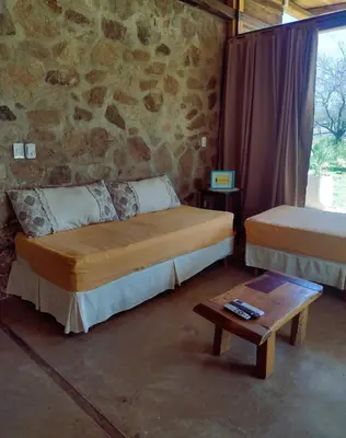 a bedroom with two beds and a table and a stone wall at La Comarca in San Javier