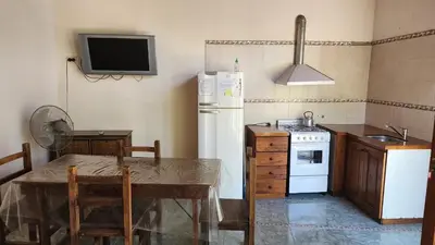 a kitchen with a table and a white refrigerator at SARA COMPLEJO in Mina Clavero