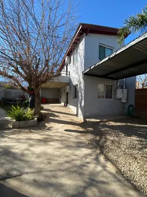 a house with a tree next to a driveway at Romedeptos I in Merlo