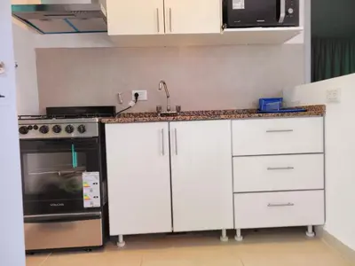 a kitchen with white cabinets and a sink and a stove at Casa Roque Funes, ubicado en Cerro de las Rosas Córdoba, Ofrece, Asador, Pileta, Cercanias, Estadio Kempes, aeropuerto Ambrosio Taravella, Orfeo Superdomo, Sanatorio Allende, Casa con 2 departamentos individuales y áreas comunes in Cordoba