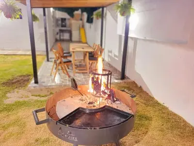 a barbecue grill in a yard with a table in the background at Casa Roque Funes, ubicado en Cerro de las Rosas Córdoba, Ofrece, Asador, Pileta, Cercanias, Estadio Kempes, aeropuerto Ambrosio Taravella, Orfeo Superdomo, Sanatorio Allende, Casa con 2 departamentos individuales y áreas comunes in Cordoba