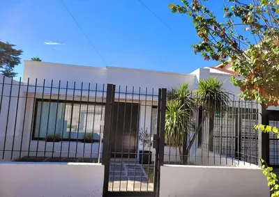 a white house with a black fence at Casa Roque Funes, ubicado en Cerro de las Rosas Córdoba, Ofrece, Asador, Pileta, Cercanias, Estadio Kempes, aeropuerto Ambrosio Taravella, Orfeo Superdomo, Sanatorio Allende, Casa con 2 departamentos individuales y áreas comunes in Cordoba