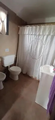 a bathroom with a toilet and a sink and a shower curtain at Casa LA SULISA in Merlo