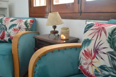 a living room with two chairs and a table with a lamp at Estancia Urbana Casa de Huéspedes in Río Cuarto