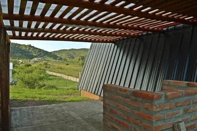 a patio with a wooden pergola and a brick wall at Complejo de Cabañas Valentino in Embalse