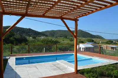 a swimming pool under a wooden pergola at Complejo de Cabañas Valentino in Embalse