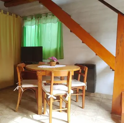 a dining room table with chairs and a television at Cabaña Providencia in Cortaderas