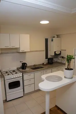 a kitchen with white cabinets and a stove top oven at Malanca - Nueva Córdoba in Cordoba