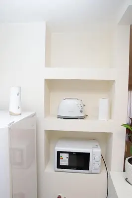 a white kitchen with a microwave and a refrigerator at Malanca - Nueva Córdoba in Cordoba