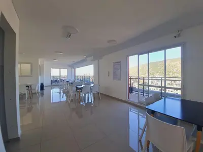 a dining room with tables and chairs and a balcony at Edificio Leonardo 6to piso in Villa Carlos Paz