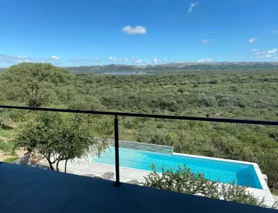 a view of a swimming pool from the balcony of a house at Sol Suites in Villa Cura Brochero