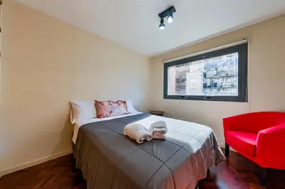 a bedroom with a bed and a red chair at Viaggiato Larrañaga II in Cordoba