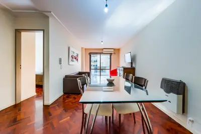 a dining room and living room with a table and chairs at Viaggiato Larrañaga II in Cordoba