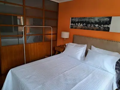 a bedroom with a white bed with an orange wall at Departamento de lujo en Cordoba Capital in Cordoba