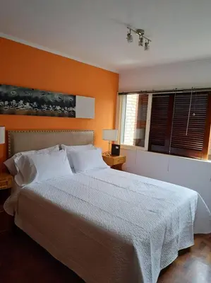 a bedroom with a large bed with an orange wall at Departamento de lujo en Cordoba Capital in Cordoba