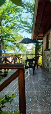 a porch with a table and an umbrella at Cabañas Don Fernando in Santa Rosa de Calamuchita