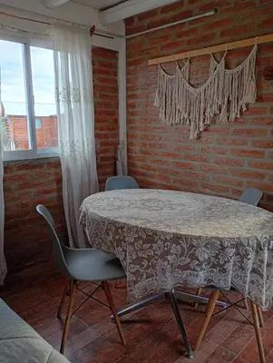 a table and chairs in a room with a brick wall at Cabañas Don Fernando in Santa Rosa de Calamuchita