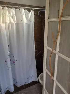 a white shower curtain in a bathroom with a toilet at Cabañas Don Fernando in Santa Rosa de Calamuchita