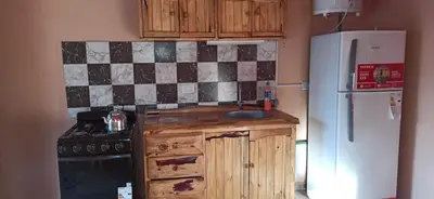 a kitchen with a refrigerator and a sink and a stove at Cabañas LAS REARTENSES in Los Reartes
