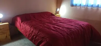 a bed with a red blanket on it in a bedroom at Cabañas LAS REARTENSES in Los Reartes