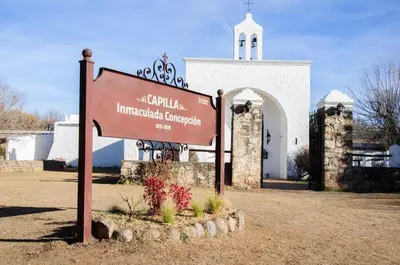 a sign in front of a building with a church at Cabañas LAS REARTENSES in Los Reartes