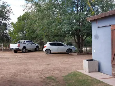 two cars parked in a parking lot next to a building at Cardozo House, casa de campo in Villa Dolores