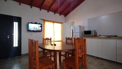 a kitchen with a table and chairs and a refrigerator at Cabañas Matilda in Los Molles