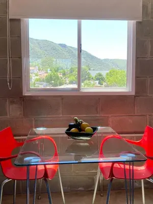 a glass table with red chairs and a window at Departamento pleno centro costanera estilo industrial único in Santa Rosa de Calamuchita