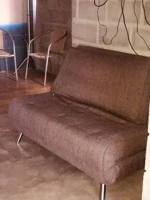 a brown couch sitting in a room with two chairs at Departamento pleno centro costanera estilo industrial único in Santa Rosa de Calamuchita