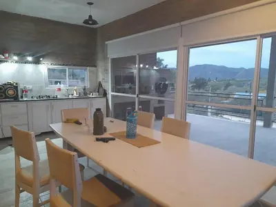 a kitchen with a table with chairs and a large window at CHALET DE SIQUIMAN in Villa Parque Siquiman